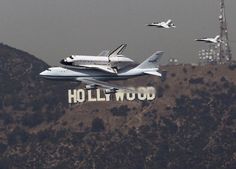 the space shuttle is on top of the hollywood sign with other planes flying around it