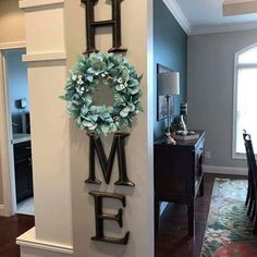 the word home is hanging on the wall next to a wreath with flowers and leaves