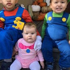 three children sitting on the ground wearing costumes