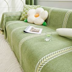 a green couch with a white flower on it and a magazine sitting on the arm