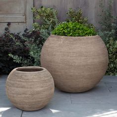 two large round planters sitting next to each other