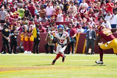 a football player running with the ball in his hand and people watching from the stands