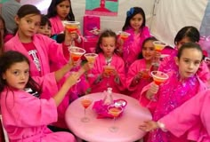 a group of girls in pink outfits holding drinks