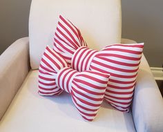 three red and white striped pillows sitting on top of a white chair in a room