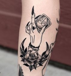 a woman's leg with a tattoo on it and a phone in her hand