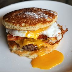 a breakfast sandwich with eggs and bacon on a white plate