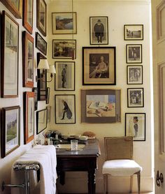 a room with many pictures on the wall and a desk in front of it,