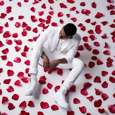 a man in white suit sitting on rose petals