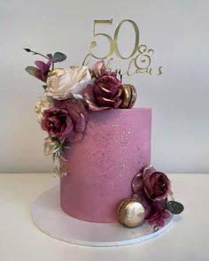 a pink and gold cake with flowers on top