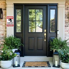 two potted plants sit on the front steps of a house with a black door