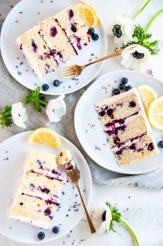 three slices of lemon blueberry cake on two white plates with flowers and spoons