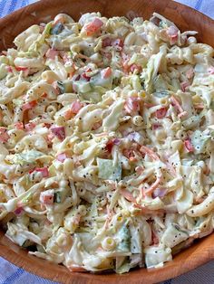 a wooden bowl filled with pasta salad on top of a blue and white table cloth