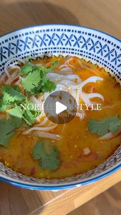 a bowl of soup with cilantro and onions in it on a wooden table