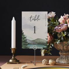 a table setting with flowers, candles and place card holders on the table in front of it