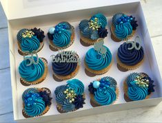 a box filled with blue frosted cupcakes covered in icing and decorations