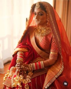 a woman in a red and gold bridal outfit