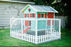 a chicken house with a white picket fence and red steps leading up to the roof