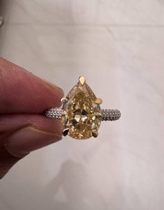 a fancy yellow diamond ring in someone's hand