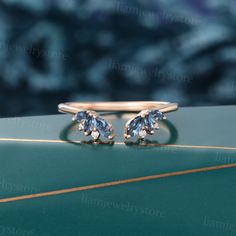 two blue and white diamond rings sitting on top of a green surface with flowers in the background