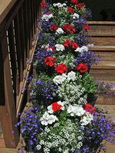 an arrangement of red, white and blue flowers on a porch