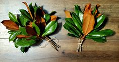 two bouquets of flowers on a wooden table with green and orange leaves tied to them