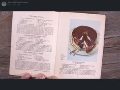 an open book with a chocolate cake on the page and a hand holding it up