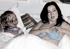 a woman laying in bed next to a child with makeup on her face and nose