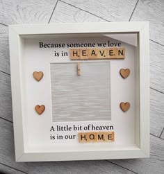 a white frame with some wooden hearts on it and a cross hanging from the side