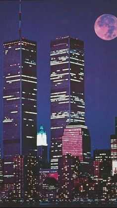 two tall skyscrapers in the city at night with a full moon behind them and buildings lit up