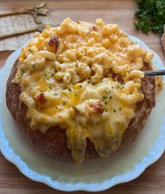 a baked potato covered in macaroni and cheese on a plate with a fork