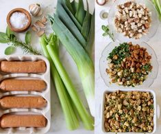 an assortment of food is displayed on a table with plates and utensils, including celery