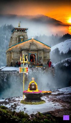 a small temple in the middle of a mountain with snow on the ground and fog rolling over it