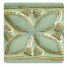 a green and gold tile with an ornate design on the bottom, it looks like a flower