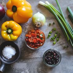 the ingredients for this dish include beans, onions, tomatoes and green onions on a table