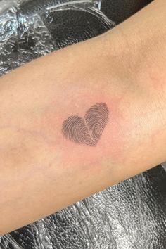 a person with a tattoo on their arm has a fingerprint in the shape of a heart