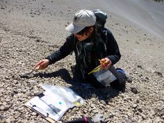 a woman is sitting on the ground with her hand out and holding something in one hand