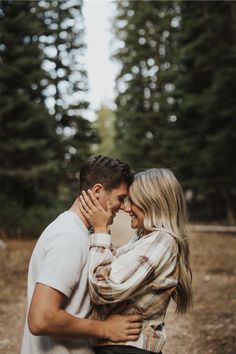 a man and woman embracing each other in the woods