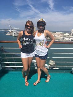 two young women standing on the deck of a cruise ship, posing for a photo