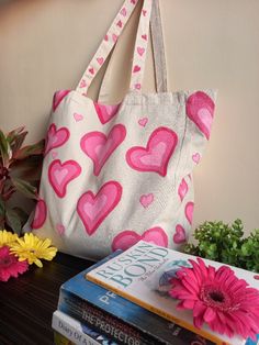 a pink and white bag sitting on top of a table next to books with flowers