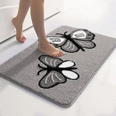 a person standing on a bathroom rug that has flowers and butterflies on it, with one foot in the floor