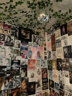 a wall covered in posters and ivy growing from it's ceiling, next to a chandelier