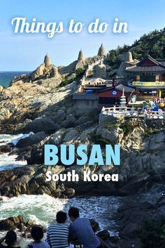 people sitting on the edge of a cliff looking out at the ocean and buildings with text overlay that reads things to do in busan south korea