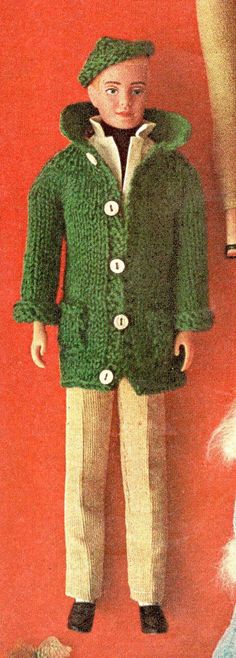 an old fashioned doll is wearing a green jacket and pants with buttons on the front