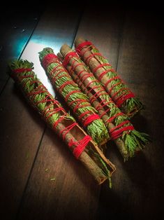 three bundles of cinnamon sticks wrapped in twine and tied with red string on top of a wooden table