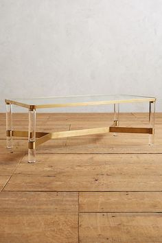 a glass and brass coffee table on a wooden floor