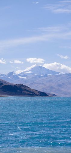 a large body of water with mountains in the backgroung and blue sky