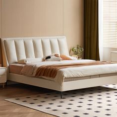 a white bed sitting next to a window on top of a wooden floor in a bedroom