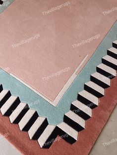 a pink rug with black and white piano keys on the bottom, in front of a light blue background