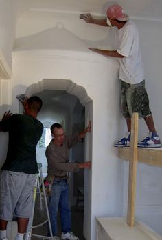 two men are painting the walls of a house