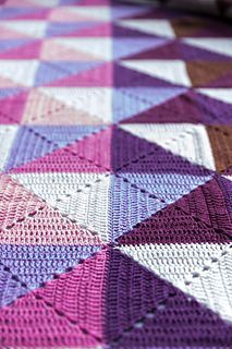 a crocheted blanket is laying on the floor